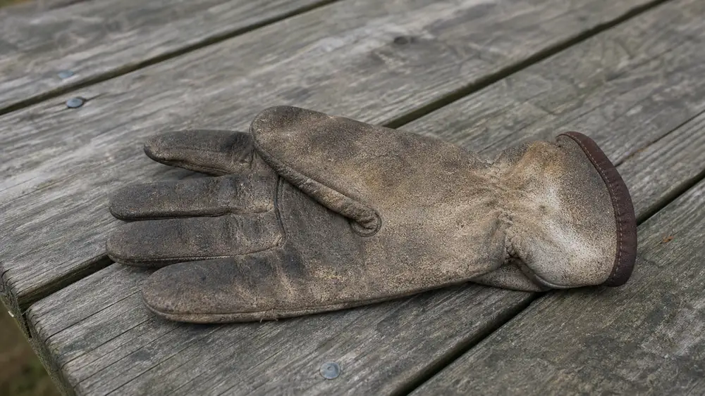 Worn black silicone BBQ glove showing a faded, slightly cracked cuff area after months of grill use